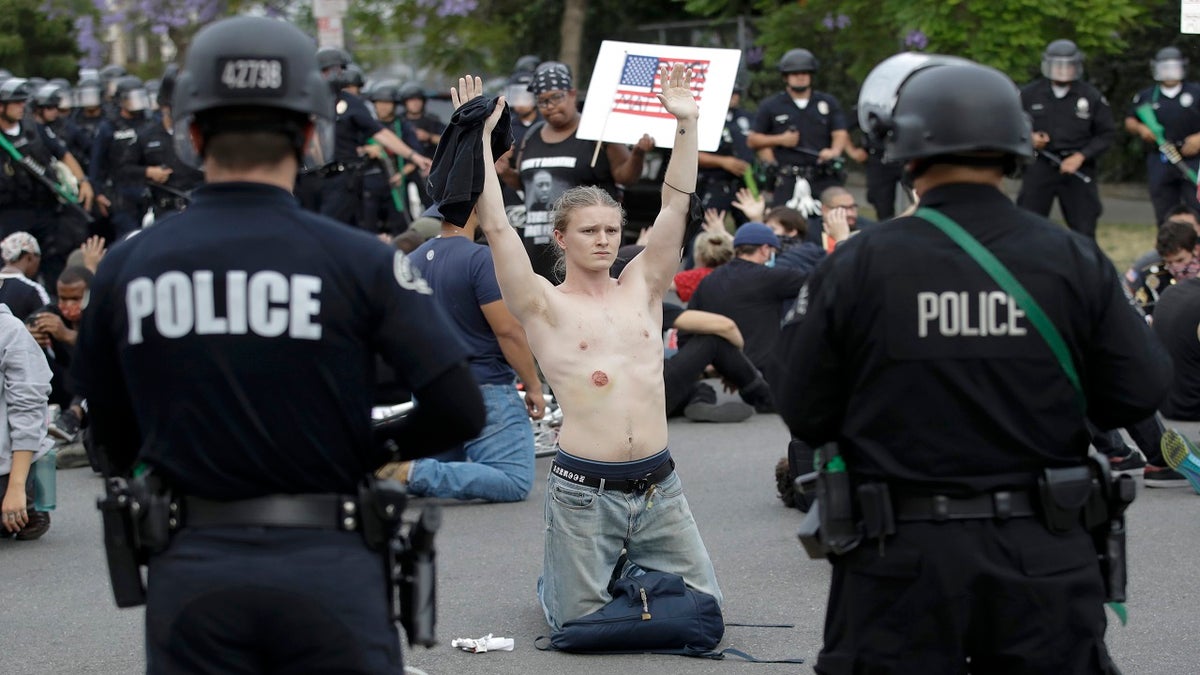 FILE - In this June 1, 2020, file photo, a protester raises his arm shortly before being arrested for violating a curfew in the Hollywood area of Los Angeles during demonstrations over the death of George Floyd. (AP Photo/Marcio Jose Sanchez, File)