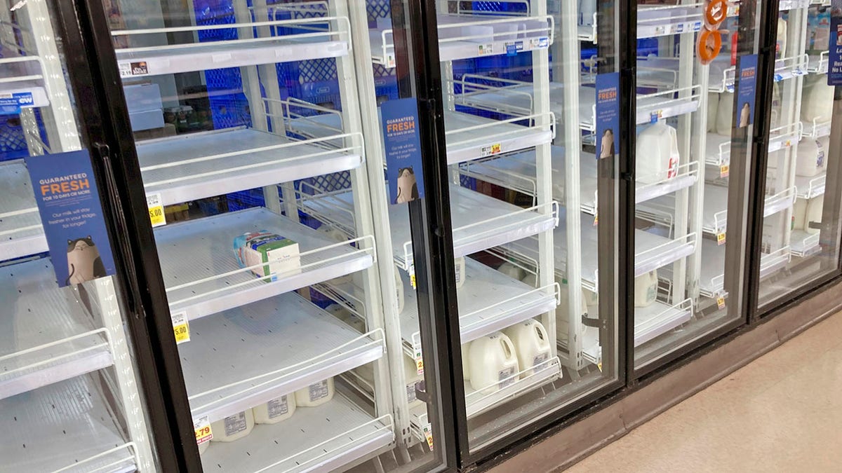The refrigerated case for milk is nearly empty at a grocery store late Thursday, March 11, 2021, in south Denver. Grocers have been overrun by shoppers as they prepare to possibly be homebound as a slow-moving storm sweeps over the intermountain West with the potential to leave two feet, or more, of snow in its wake. (AP Photo/David Zalubowski)
