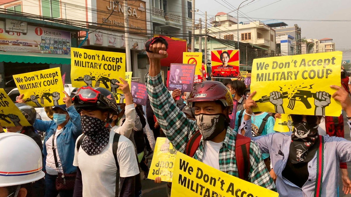 Anti-coup protesters hold signs that read, "We don't accept military coup," during a march in Mandalay, Burma, Sunday, March 14, 2021. The civilian leader of Burma's government in hiding vowed to continue supporting a "revolution" to oust the military that seized power in last month's coup, as security forces again met protesters with lethal forces, killing several people. (AP Photos)
