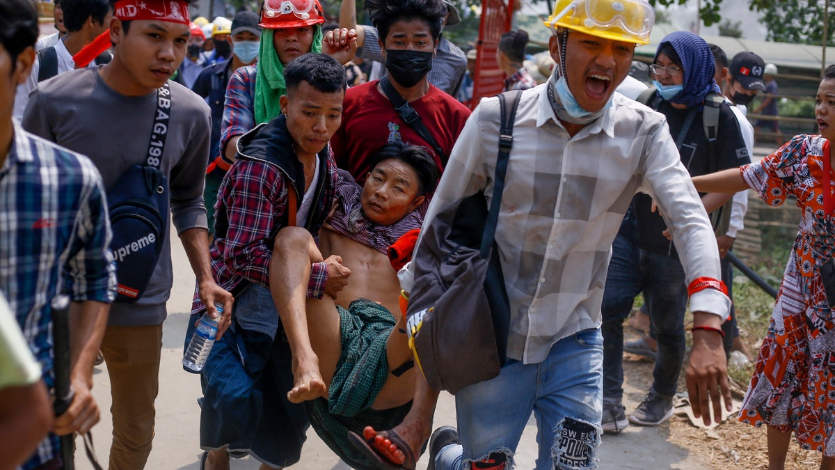 Anti-coup protesters carry an injured man following clashes with security in Yangon, Burma Sunday, March 14, 2021. The civilian leader of Burma's government in hiding vowed to continue supporting a "revolution" to oust the military that seized power in last month's coup, as security forces again met protesters with lethal forces, killing several people. (AP Photo)