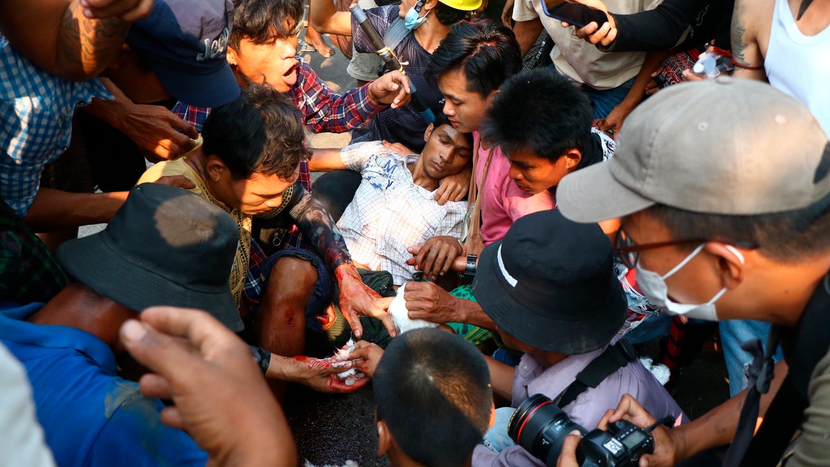 Anti-coup protesters surround an injured man in Hlaing Thar Yartownship in Yangon, Burma Sunday, March 14, 2021. A number of people were shot dead during protests in Burma's largest city on Sunday, as security forces continued their violent crackdown against dissent following last month's military coup. (AP Photo)