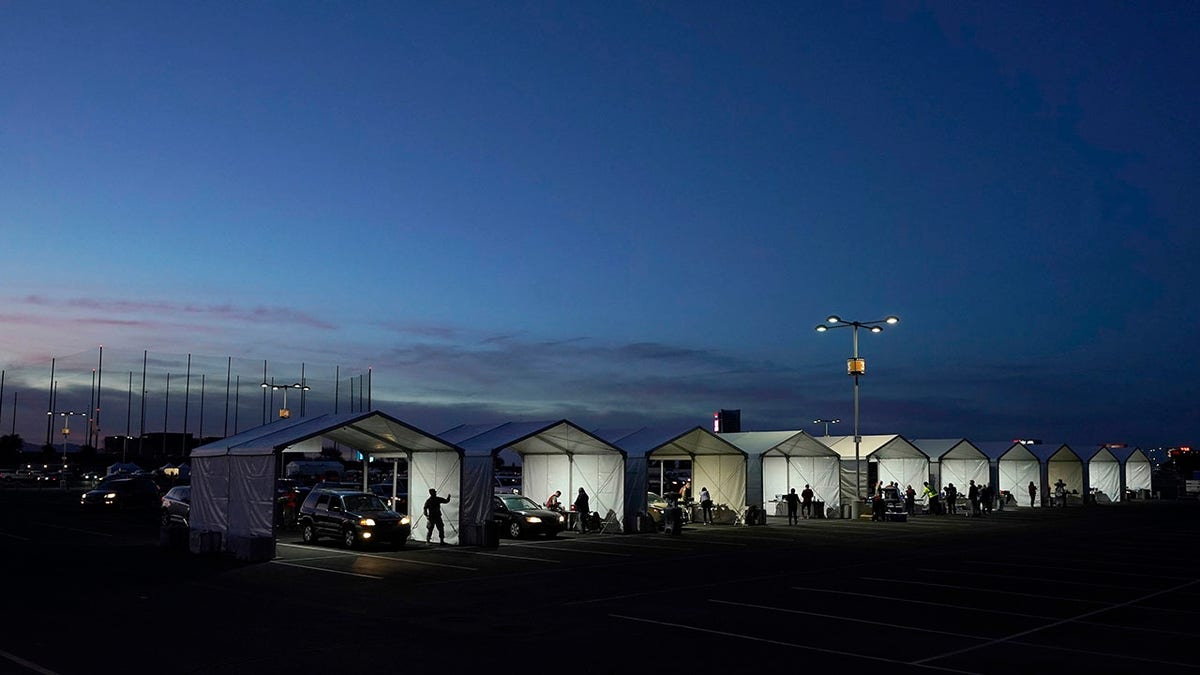 In this Jan. 12, 2021, file photo, several tents are set up so people who have registered can get their COVID-19 vaccinations as they drive-thru the parking lot of the State Farm Stadium in Glendale, Arizona. (AP Photo/Ross D. Franklin)