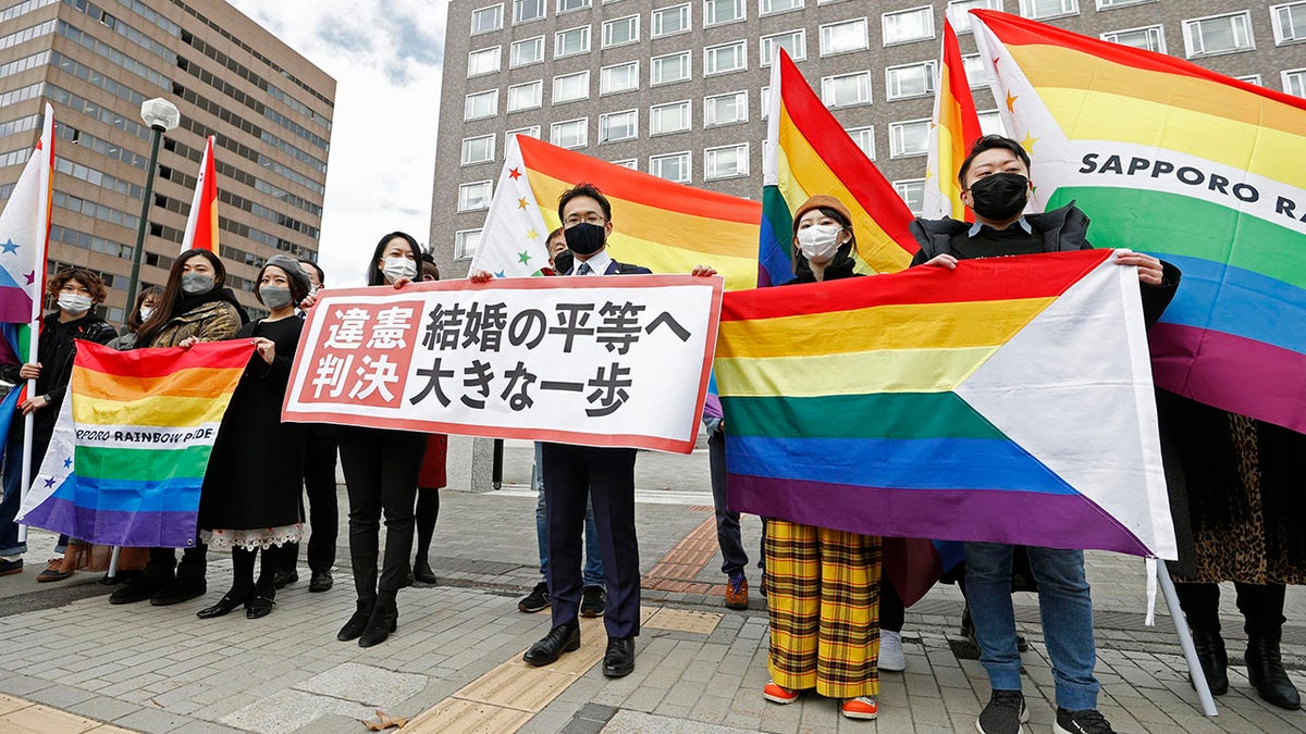 Plaintiffs' lawyers and supporters hold rainbow flags and a banner that reads: "Unconstitutional judgment" outside Sapporo District Court after a court rule, in Sapporo, northern Japan, Wednesday, March 17, 2021. The court ruled the government's ban on same-sex marriages is unconstitutional, recognizing the rights of same-sex couples for the first time in the only Group of Seven country that doesn't acknowledge their legal partnership. (Yohei Fukai/Kyodo News via AP)