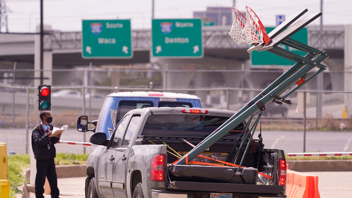 A security guard at the Kay Bailey Hutchison Convention Center checks in vehicles carrying basketball hoops Thursday, March 18, 2021, in Dallas. (AP Photo/LM Otero)