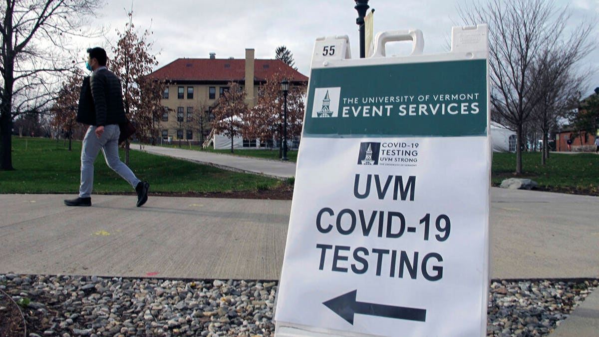 FILE: A University of Vermont student walks toward a tent leading to a COVID-testing site on campus in Burlington, Vt. 