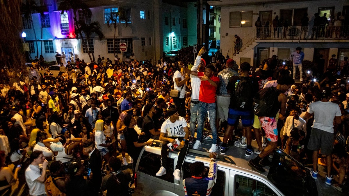 Crowds defiantly gather in the street while a speaker blasts music an hour past curfew in Miami Beach, Fla., on Sunday. An 8 p.m. curfew has been extended in Miami Beach after law enforcement worked to contain unruly crowds of spring break tourists. (Daniel A. Varela/Miami Herald via AP)