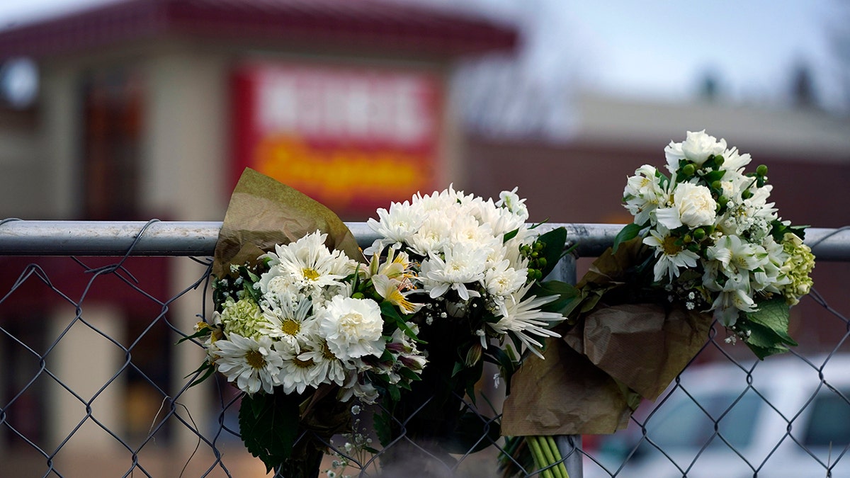 Bouquets line a fence put up around the parking lot where a mass shooting took place the day before in a King Soopers grocery store, Tuesday, March 23, 2021, in Boulder, Colo. (AP Photo/David Zalubowski)