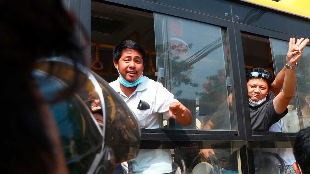 An arrested protester flashes the three-fingered salute while onboard a bus getting out of Insein prison to go to an undisclosed location Wednesday, March 24, 2021 in Yangon, Burma. (AP Photo)