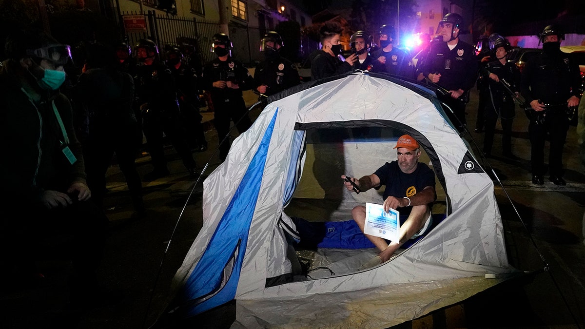 A demonstrator sets up a tent in front of police in the Echo Park section of Los Angeles Thursday, March 25, 2021. Demonstrators gathered to protest the planned temporary closure of a Los Angeles park that would displace a large homeless encampment, which has grown throughout the coronavirus pandemic.