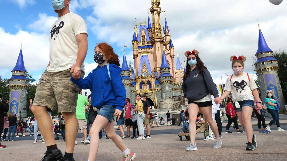 A family walks past Cinderella Castle in the Magic Kingdom, at Walt Disney World in Lake Buena Vista, Fla. (Joe Burbank/Orlando Sentinel via AP, File)