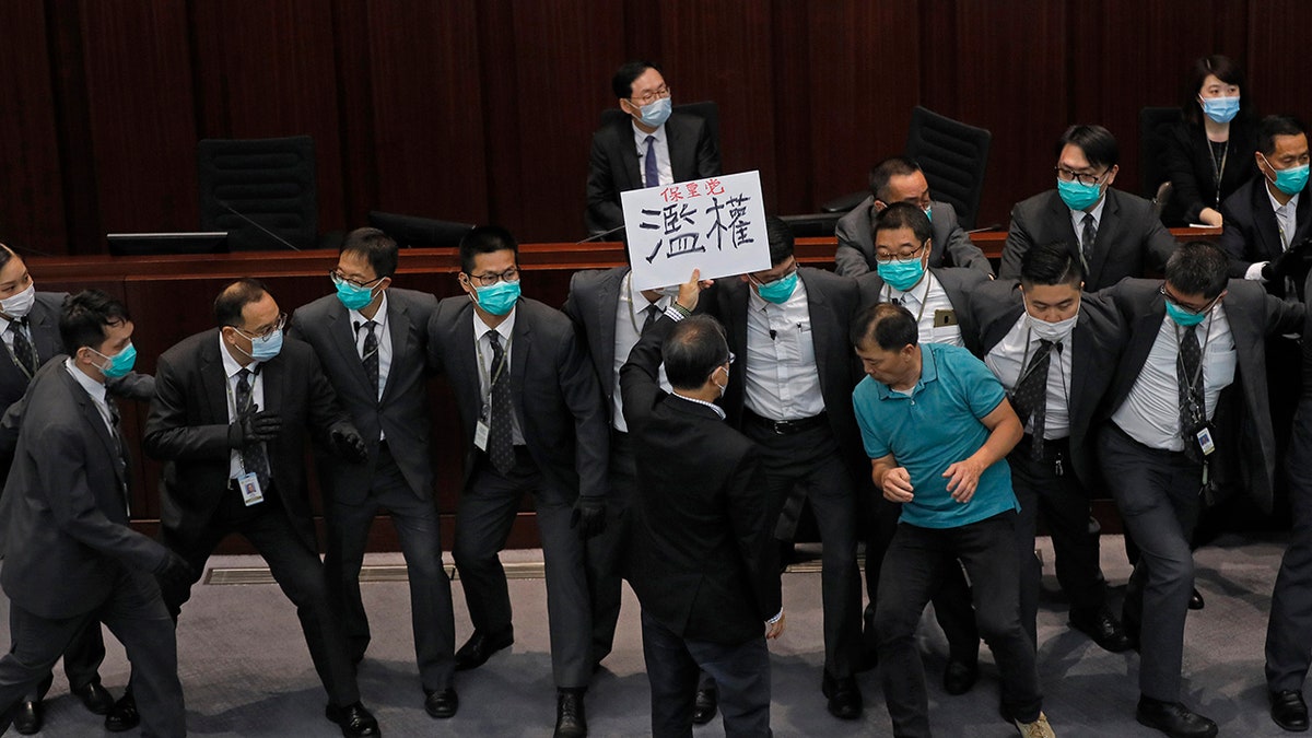 Pro-democracy lawmaker Wu Chi-wai, right in a polo shirt, scuffles with security guards during a Legislative Council's House Committee meeting in Hong Kong on May 18, 2020. (AP Photo/Vincent Yu, File)