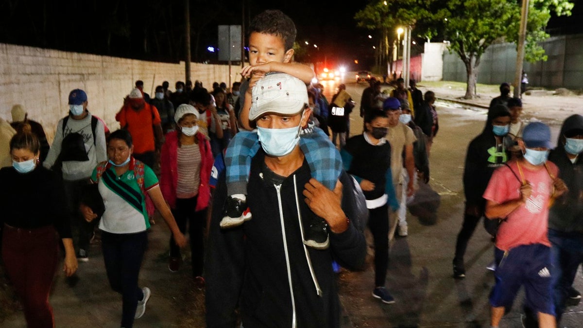 Migrants who aim to reach the U.S. walk along a highway as they leave San Pedro Sula, Honduras before dawn Tuesday.