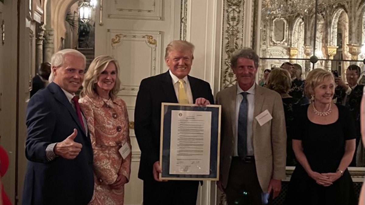 Former President Trump is given a framed resolution at Mar-a-Lago. (Perry Hooper Jr.)