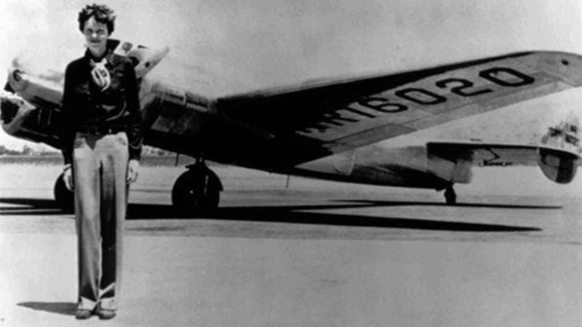 Black and white photo of Amelia Earhart in front of a plane