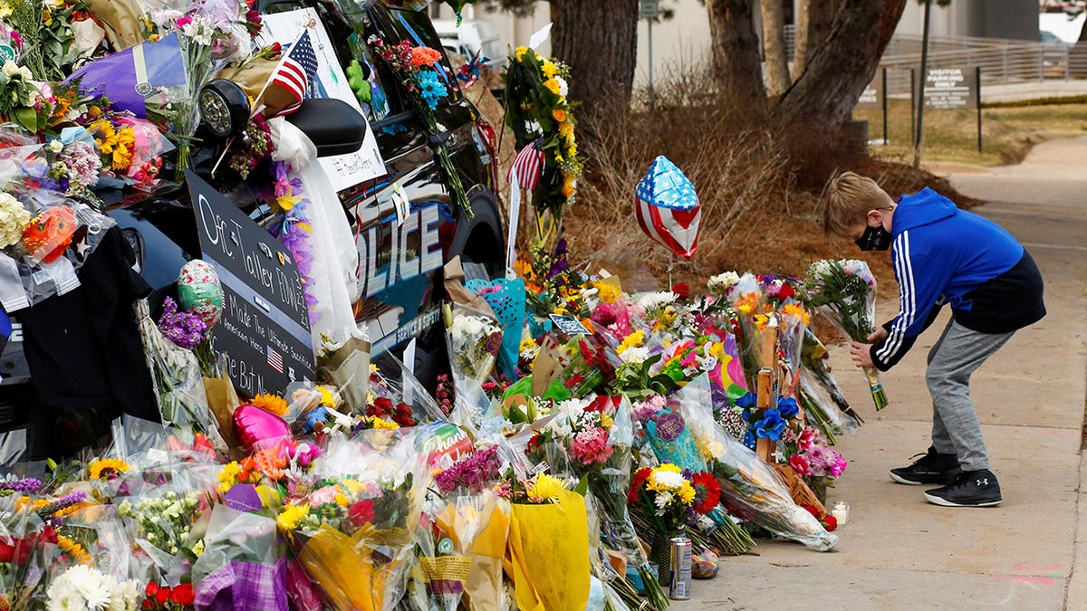 A child lays flowers near the police car of officer Eric Talley who died Monday responding to a call where a gunman opened fire on people in a King Soopers grocery store in Boulder, Colorado, U.S. March 24, 2021.