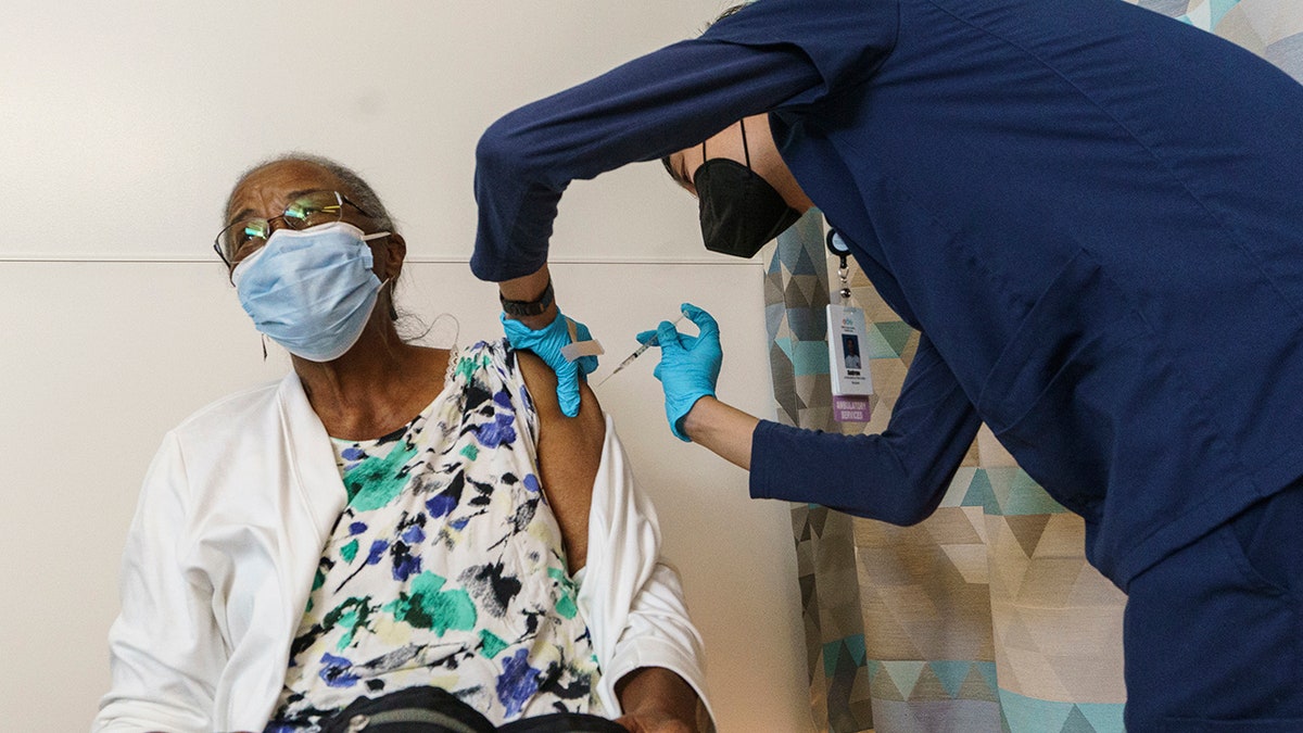 Nursing student Andrew Wong, right, vaccinates South Los Angeles resident Annie Carmichael with her first dose of the Pfizer COVID-19 vaccine to prevent the coronavirus at the MLK Community Medical Group clinic in Los Angeles, Wednesday, Feb. 24, 2021. (AP Photo/Damian Dovarganes)