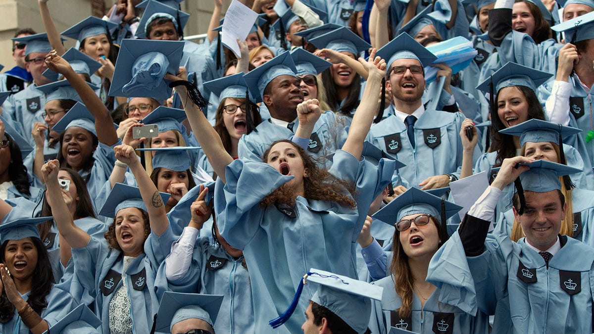 Photo shows Columbia University graduates in their gowns celebrating earning their degrees