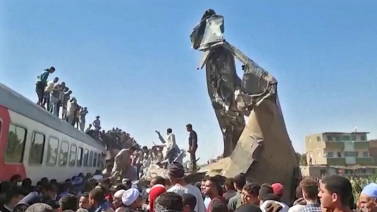 This screengrab provided by AFPTV ahows people gathered around the wreckage of two trains that collided in the Tahta district of Sohag province, some 285 miles south of Cairo, killing at least 32 people and injuring scores of others, on March 26, 2021. 