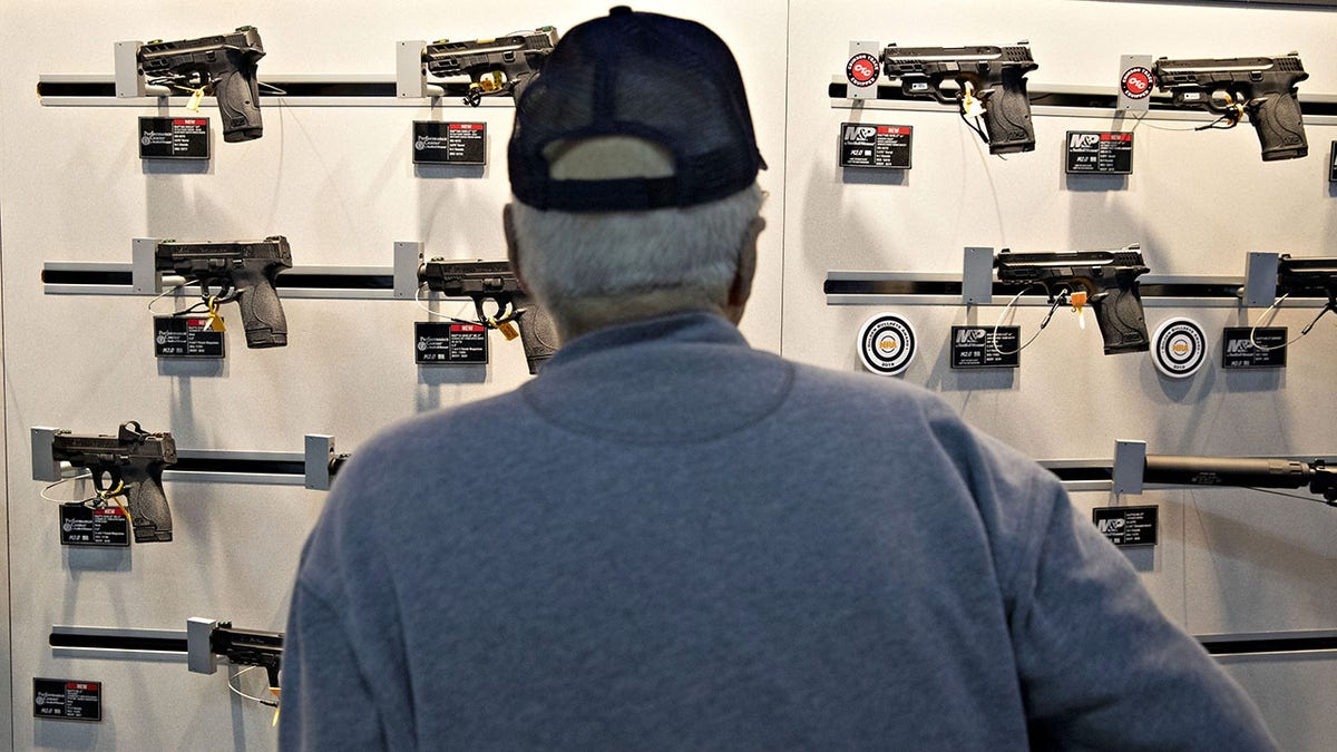 Man looking at NRA display of pistols