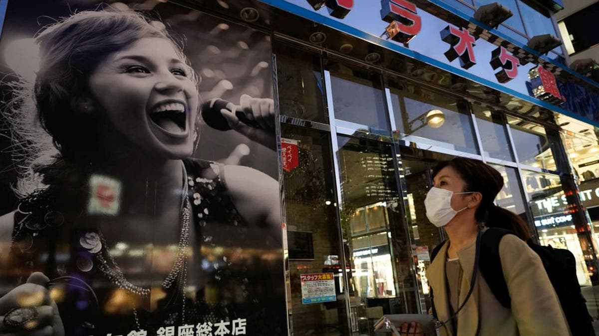 Pictured here is a masked woman walking by a closed karaoke establishment in Tokyo's upscale Ginza district in April 2020. Many karaoke bars had shuttered operations under former Prime Minister Shinzō Abe's previous state of emergency. (Christopher Jue/Getty Images)