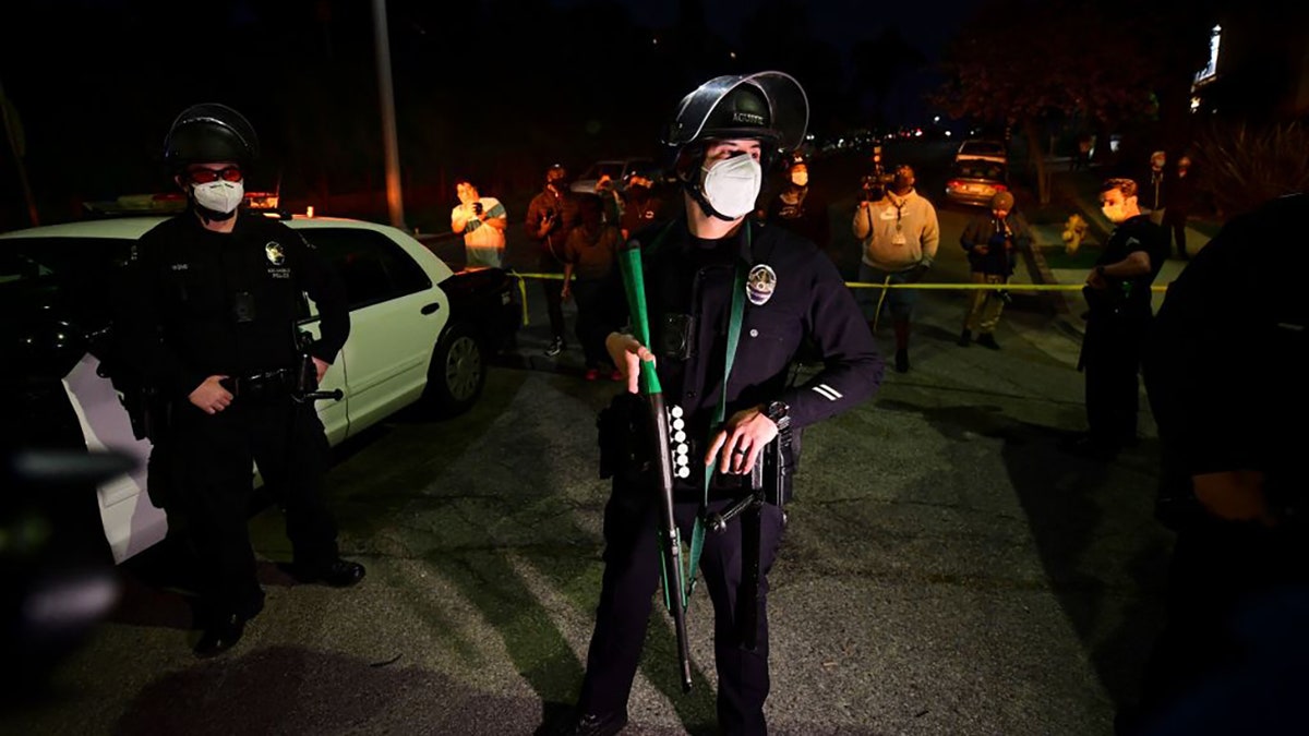 An LAPD officer holds a rubber-bullet gun on scene at Echo Park Lake in Los Angeles, March 24, 2021, ahead of a planned and announced cleanup of the encampment as part of an estimated half-million-dollar City of Los Angeles cleanup and repair effort. (Photo by Frederic J. BROWN / AFP) (Photo by FREDERIC J. BROWN/AFP via Getty Images)