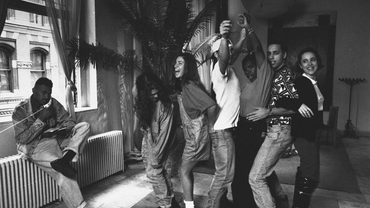 Twentysomething non-actor cast of MTV documentary 'The Real World'. (L-R) Kevin Powell talking on the phone as roomies Andre Comeau, Julie Oliver, Eric Nies, Heather Gardner, Norm Korpi, & Becky Blasband form a conga line in their trendy SoHo loft.