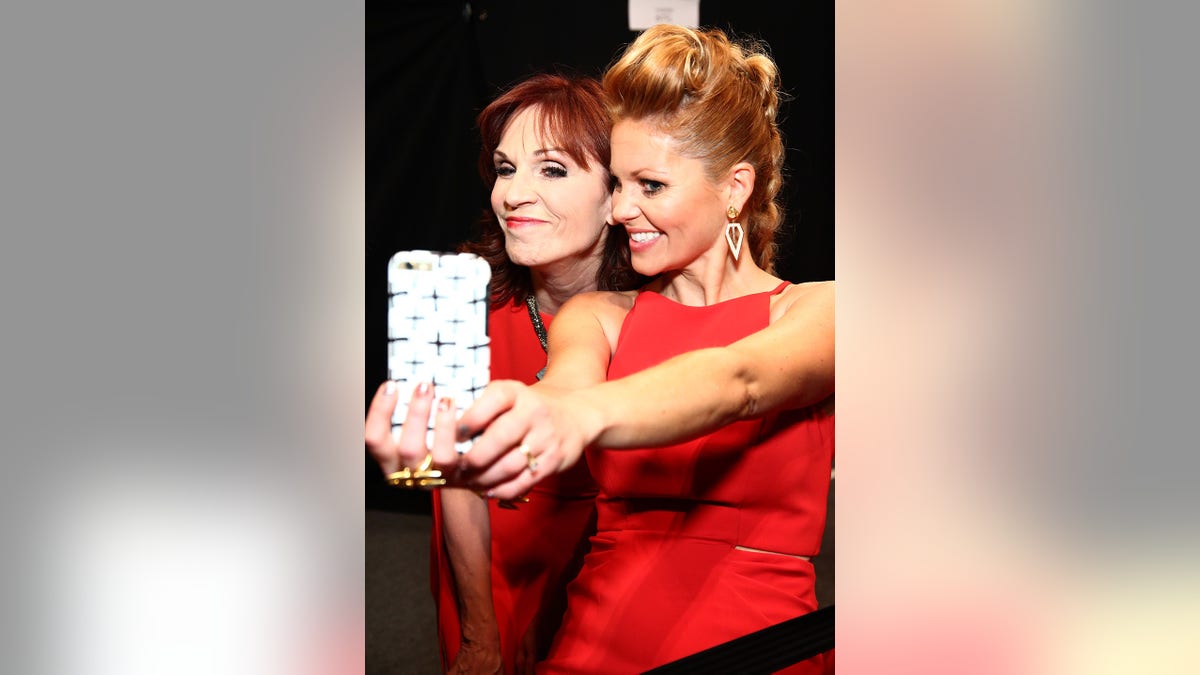 Actresses Marilu Henner and Candace Cameron Bure pose backstage at The American Heart Association's Go Red For Women Red Dress Collection 2016 Presented By Macy's at The Arc, Skylight at Moynihan Station on February 11, 2016, in New York City.