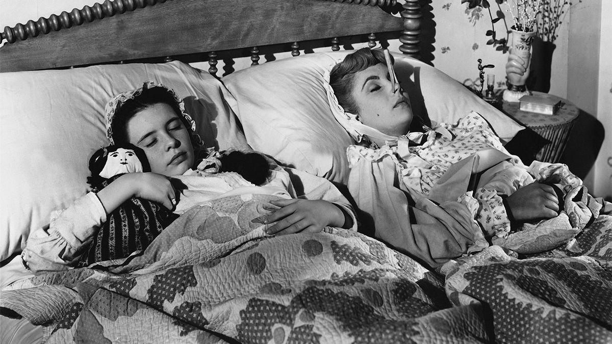 Margaret O'Brien (left) and Elizabeth Taylor forget their troubles in dreams in this scene from MGM's Technicolor production of Louisa May Alcott's 'Little Women'. The clothespin on Taylor's nose is a beauty secret of the time - purported to give the wearer a seemingly slimmer nose. The movie was produced and directed by Mervyn LeRoy. 