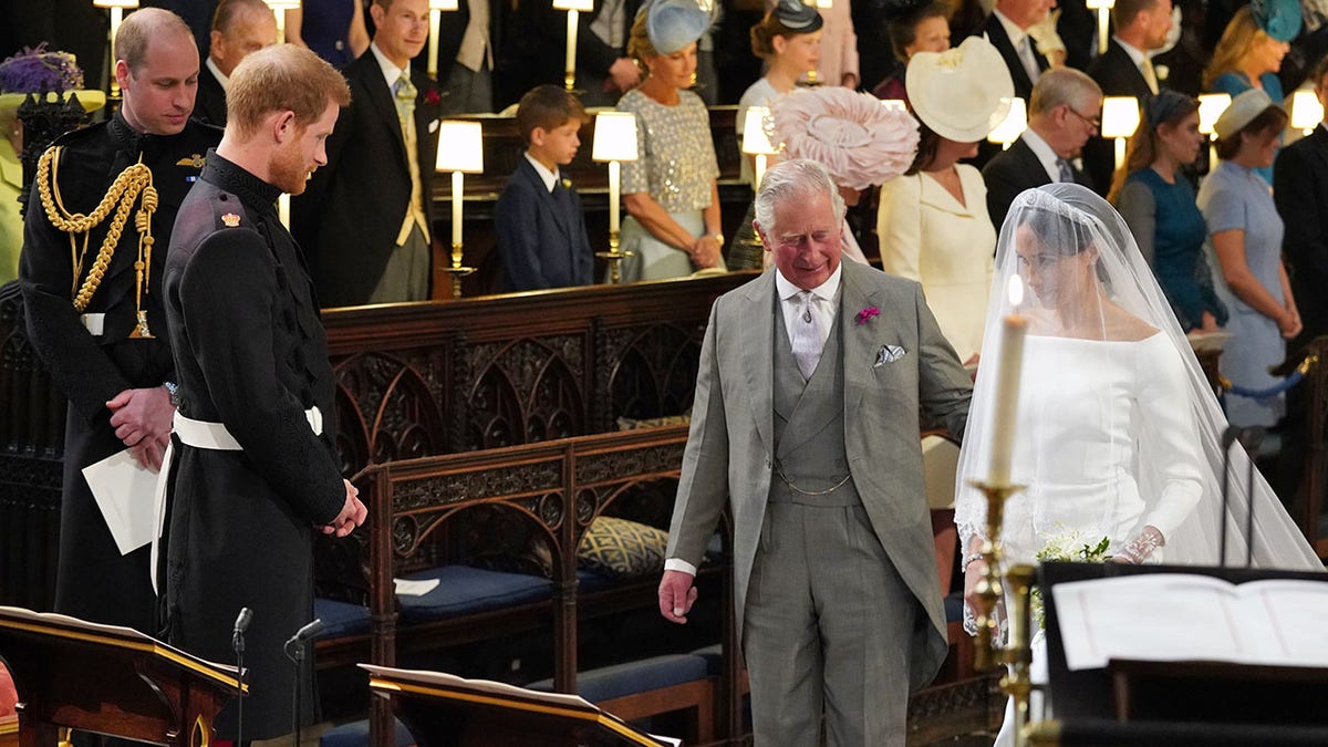 Prince Harry looks at his bride, Meghan Markle, as she arrives accompanied by Prince Charles, Prince of Wales during their wedding in St George's Chapel at Windsor Castle on May 19, 2018, in Windsor, England.