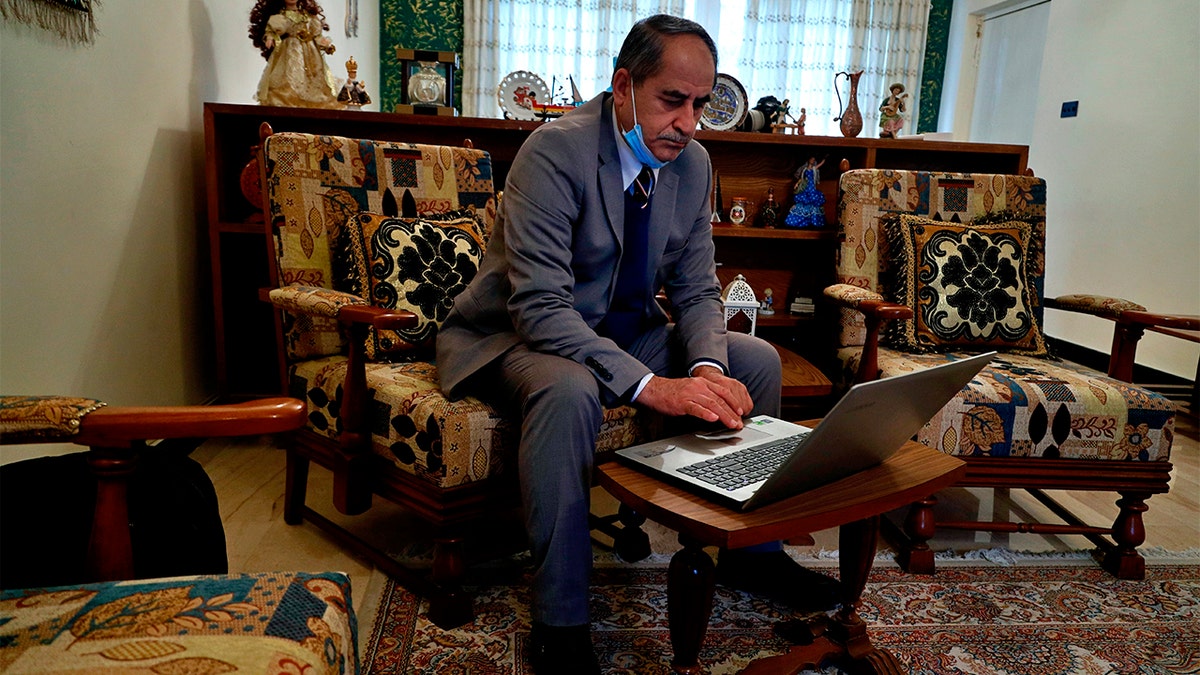 Louis Clemis reviews photos of the storming of the church on his laptop during an interview with The Associated Press in Baghdad, Iraq, Sunday, Feb. 17, 2021. (AP Photo/Hadi Mizban)