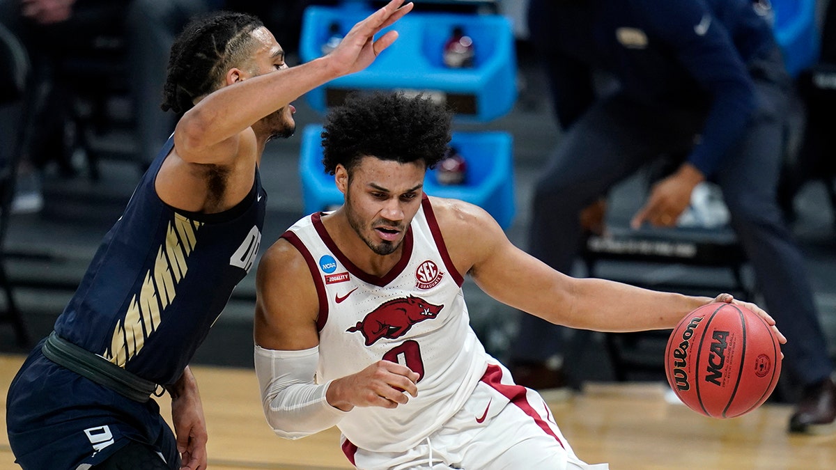Arkansas forward Justin Smith (0) drives around Oral Roberts forward Kevin Obanor, left, during the first half of a Sweet 16 game in the NCAA men's college basketball tournament at Bankers Life Fieldhouse, Saturday, March 27, 2021, in Indianapolis.