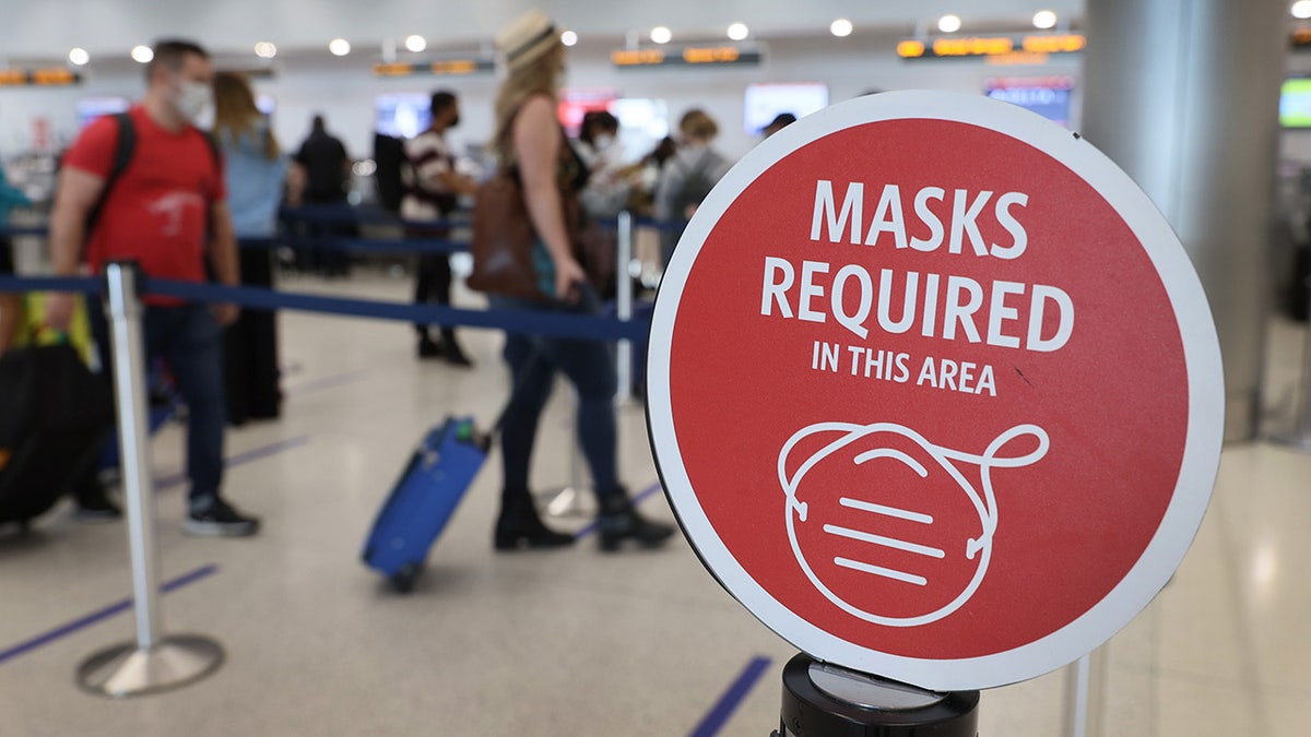 MIAMI, FLORIDA - FEBRUARY 01: A sign reading, 'masks required in this area,' is seen as travelers prepare to check-in for their Delta Airlines flight at the Miami International Airport. (Photo by Joe Raedle/Getty Images)