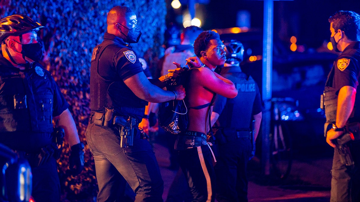 A man is arrested while out a few hours past curfew in Miami Beach, Fla., on Sunday, March 21, 2021. Miami Beach commissioners voted unanimously Sunday to extend the 8 p.m. to 6 a.m. curfew Thursday through Sunday in the South Beach entertainment district until at least April 12, effectively shutting down a spring break hot spot in one of the few states fully open during the pandemic. (Daniel A. Varela/Miami Herald via AP)