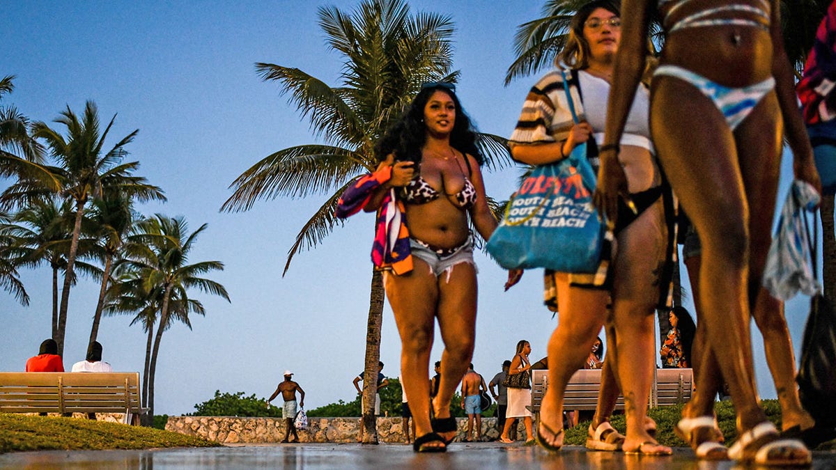 Personas caminan por Ocean Drive antes del toque de queda en Miami Beach, Florida, el 25 de marzo de 2021. 