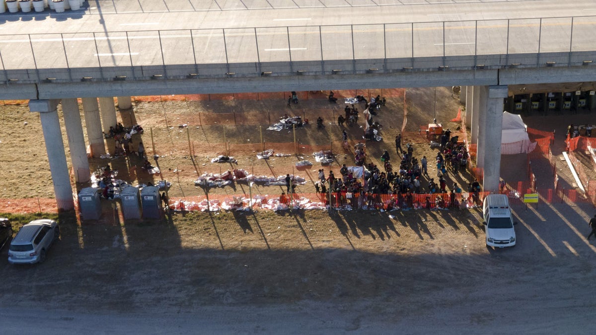 In this photo taken by a drone, migrants are seen in custody at a U.S. Customs and Border Protection processing area under the Anzalduas International Bridge, Thursday, March 18, 2021, in Mission, Texas. . (AP Photo/Julio Cortez)