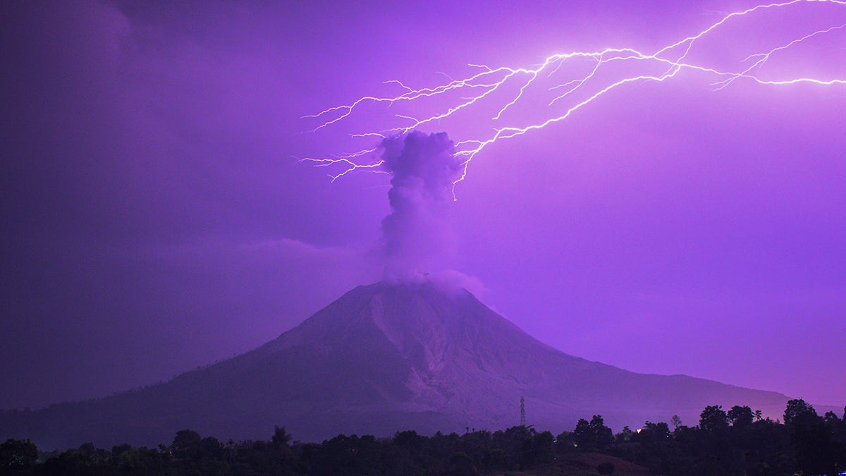 The long-time exposure photo taken on March 5, 2021 shows lightning striking near Mount Sinabung with white smoke being spewed in Karo, North Sumatra, Indonesia. (Photo by Sarianto Sembiring/Xinhua via Getty) ​​​​​