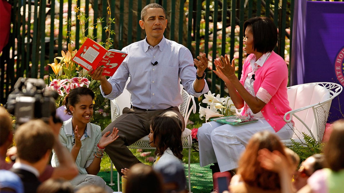 President And Mrs. Obama Host Easter Egg Roll On White House Lawn WASHINGTON - APRIL 05: U.S. President Barack Obama (C) gets a round of applause after reading "Green Eggs and Ham," by Dr. Suess, for a group of children and his family, first lady Michelle Obama (R) and daughters Malia Obama (L), 11, and Sasha Obama, 8, during the Easter Egg Roll at the White House April 5, 2010 in Washington, DC. About 30,000 people are expected to attend attended the 132-year-old tradition of rolling colored eggs down the South Lawn of the White House. (Photo by Chip Somodevilla/Getty Images)