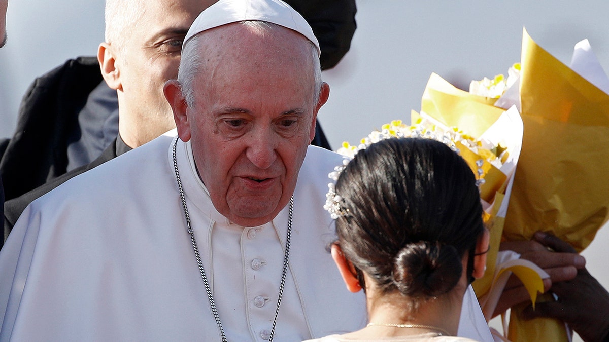 Children give Pope Francis, center, flowers as he arrives at Irbil International Airport, Iraq, Sunday, March 7, 2021. Francis is urging Iraq’s long-suffering Christians to forgive the injustices committed against them by Muslim extremists. He asks them to persevere to rebuild the country after years of war and sectarian conflicts. (AP Photo/Hadi Mizban)