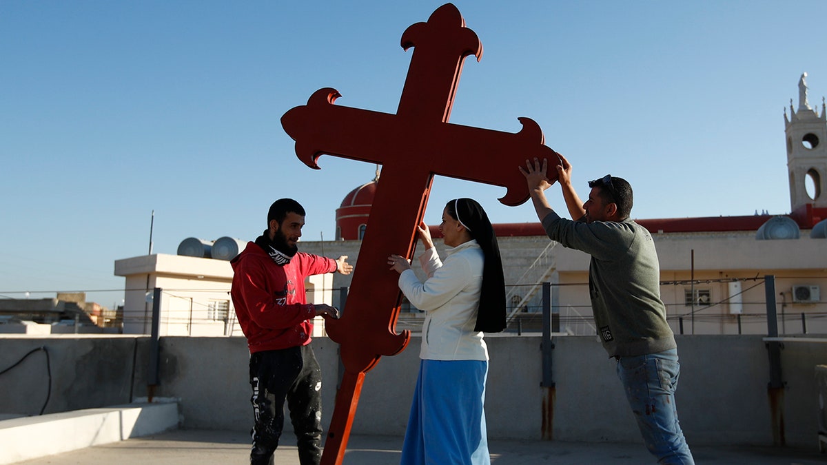 Iraqi Christians place a cross on a church in Qaraqosh, Iraq. Christians in some parts of the world continue to face persecution, similar to the audience of the First Epistle of Peter, according to faith leaders.