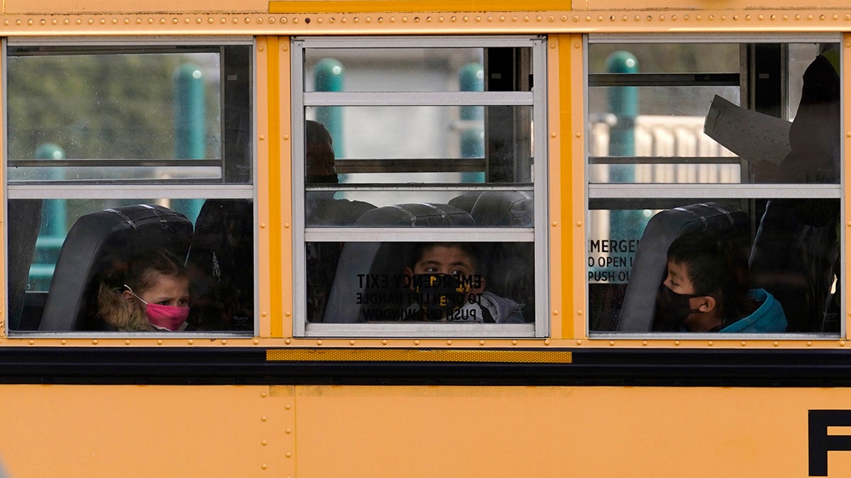 FILE - In this Thursday, Nov. 19, 2020, file photo, elementary school students sit on board a school bus after attending in-person classes at school in Wheeling, Ill. (AP Photo/Nam Y. Huh, File)