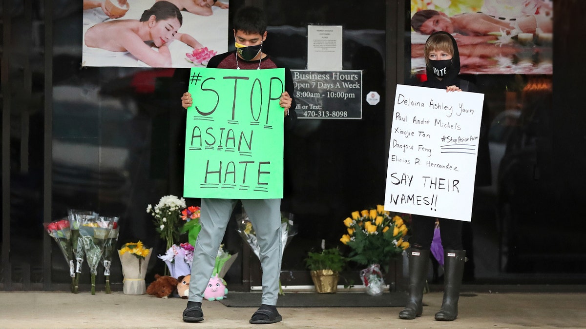 After dropping off flowers Jesus Estrella, left, and Shelby stand in support of the Asian and Hispanic community outside Young's Asian Massage Wednesday, March 17, 2021, in Acworth, Ga. (Curtis Compton /Atlanta Journal-Constitution via AP)