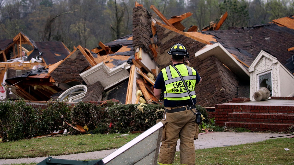 A firefighter surveys damage to a house where the family was trapped, but were able to get out after a tornado touches down south of Birmingham, Ala. in the Eagle Point community damaging multiple homes Thursday, March 25, 2021.