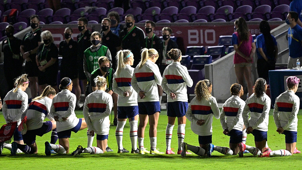 Some members of the United States team kneel during the playing of the national anthem before a SheBelieves Cup women's soccer match against Canada, Thursday, Feb. 18, 2021, in Orlando, Fla. (AP Photo/Phelan M. Ebenhack)