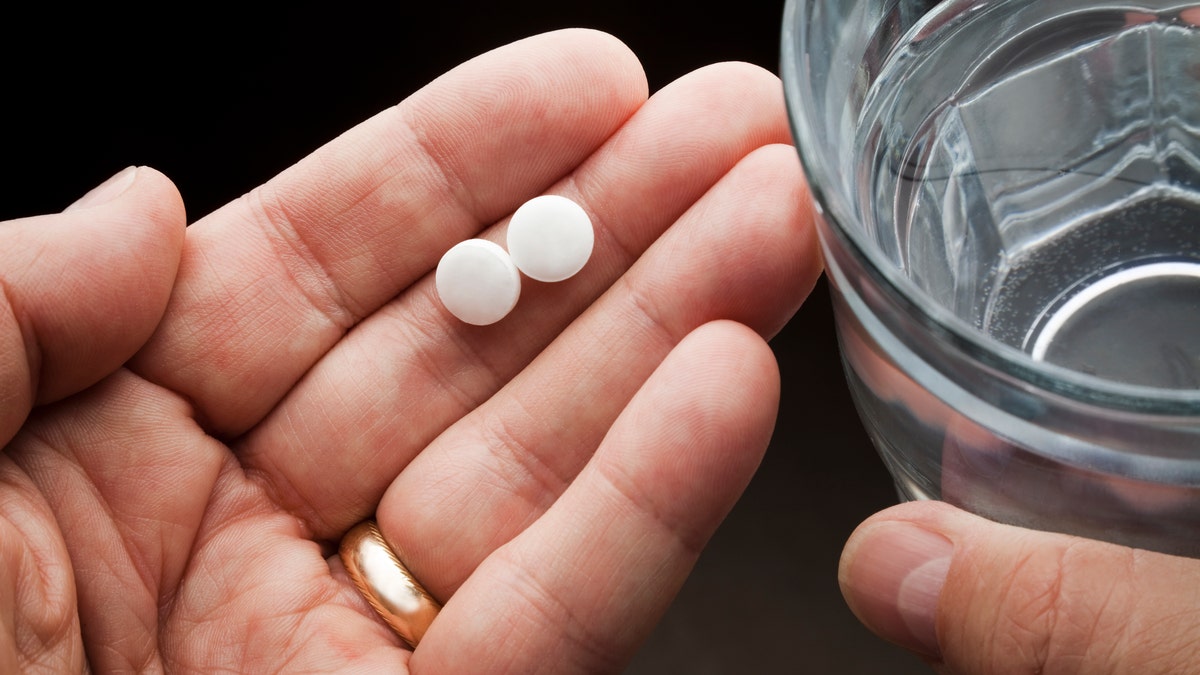 Aspirin pills in person's hand