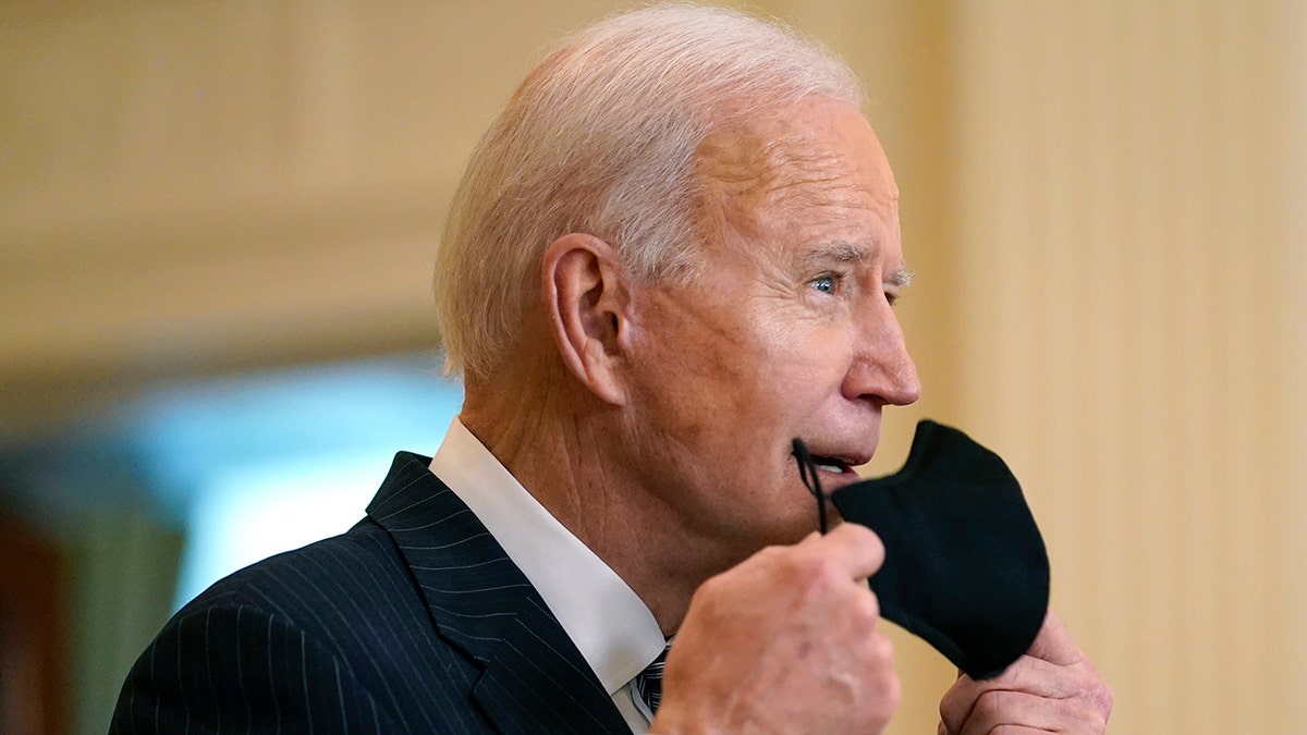 President Joe Biden removes his face mask as he arrives to speak about COVID-19 vaccinations from the East Room of the White House on March 18, 2021. (AP Photo/Andrew Harnik)