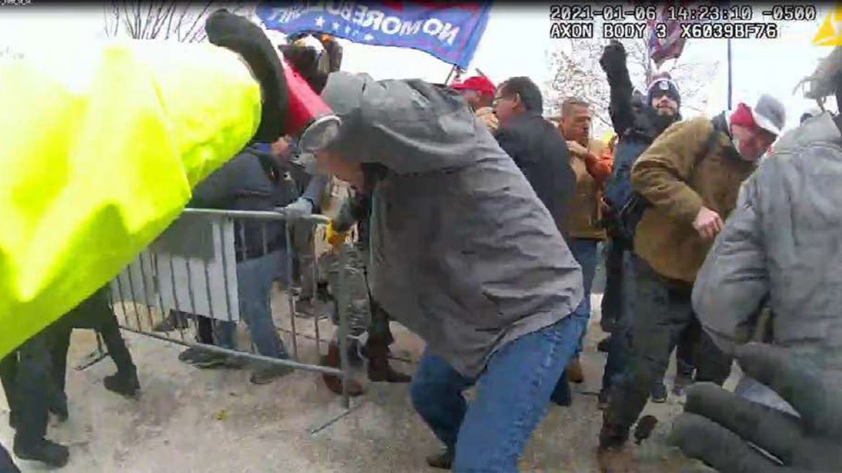 Julian Elie Khater, with his right arm in the air, appears to be holding a canister in his right hand and aiming it in the officers' direction, prosecutors say.