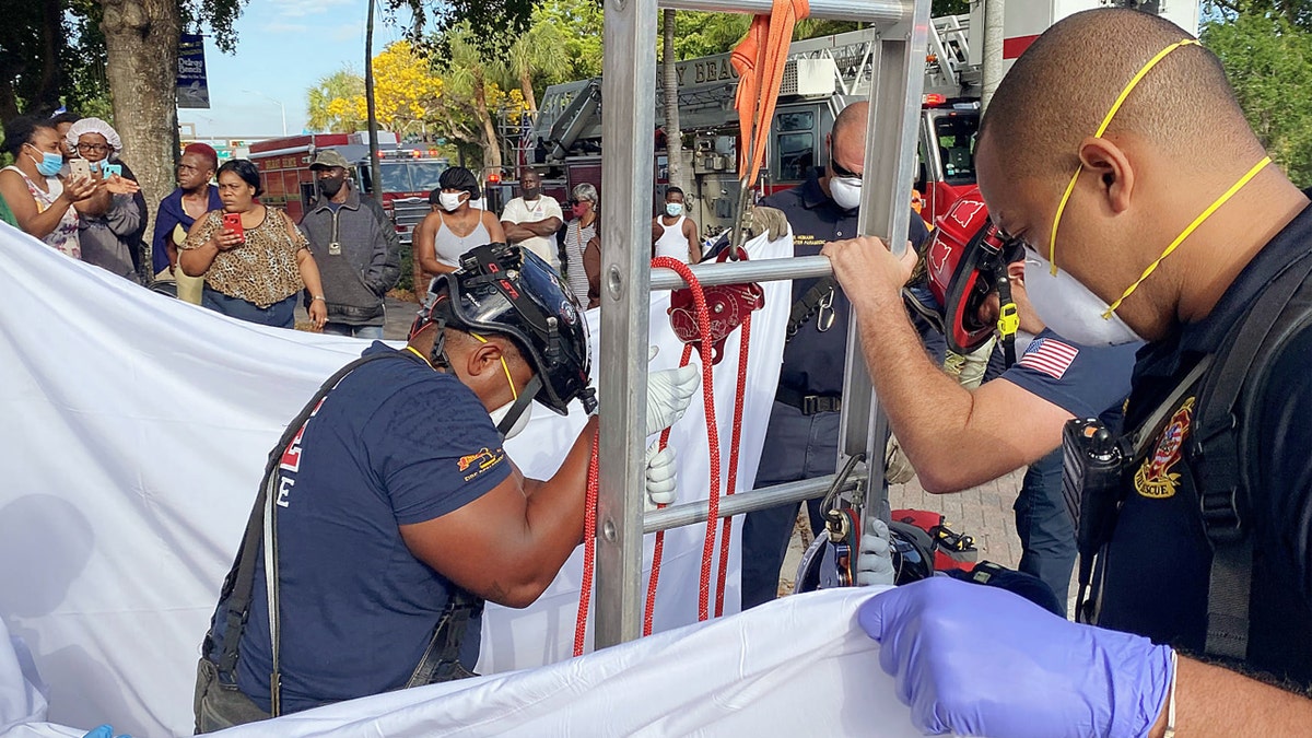 First responders held up a sheet for the victim's privacy as onlookers cheered her rescue.