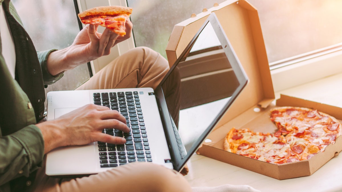 Man eating pizza while working