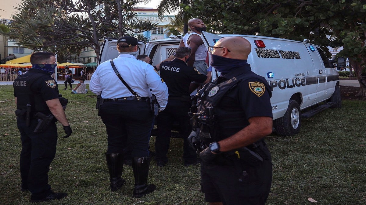 An unidentified man is detained and later arrested on Sunday at 5th Street and Ocean Drive in Miami Beach. (AP/Miami Herald)