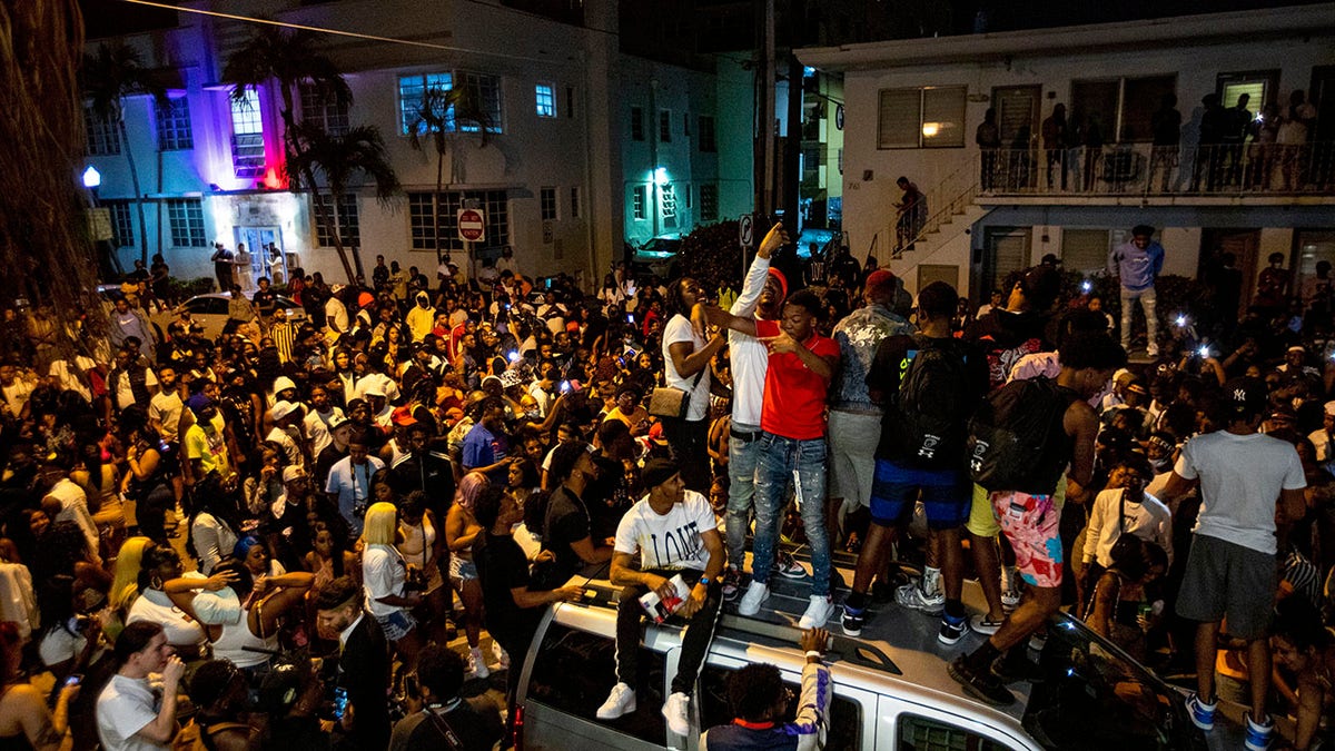 Crowds defiantly gather in the street while a speaker blasts music an hour past curfew in Miami Beach, Fla., on Sunday. (Daniel A. Varela/Miami Herald via AP)